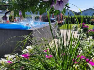 a swimming pool in a garden with pink flowers at Białe Domki in Sarbinowo