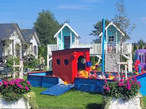 a playground in a yard with a house at Białe Domki in Sarbinowo