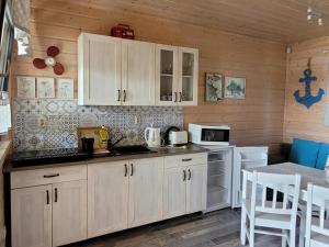 a kitchen with white cabinets and white appliances at Białe Domki in Sarbinowo