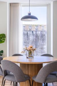 ヴィアナ・ド・カステロにあるMexia Galvão city centerの椅子と花瓶が置かれたダイニングテーブル