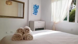 een witte slaapkamer met handdoeken op een bed bij La Cala Mijas Cozy Apartment in La Cala de Mijas