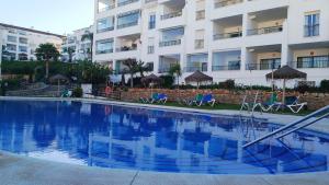 een zwembad met stoelen en parasols voor een gebouw bij La Cala Mijas Cozy Apartment in La Cala de Mijas