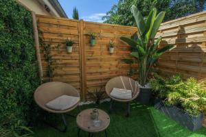 zwei Stühle und ein Tisch vor einem Zaun in der Unterkunft Love Room avec spa in Bourg-Saint-Christophe