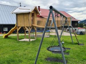 a playground with a slide and a wooden house at Ferienhof "Alpe Berg" in Balderschwang