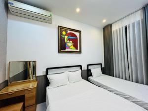 two beds in a room with a tv at MUN HOMESTAY in Hue