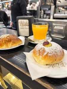 Dos pasteles en platos sobre un mostrador con un vaso de jugo de naranja. en Casa Margherita, en Nápoles