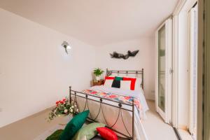 Schlafzimmer mit einem Bett mit roten und grünen Kissen in der Unterkunft Villa Sanssouci 8, Emma Villas in Castrignano del Capo