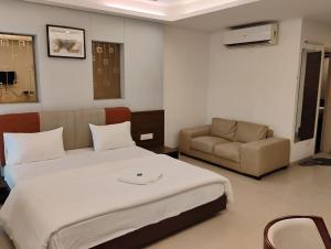 a bedroom with a large bed and a couch at hotel nova haven in Ankleshwar