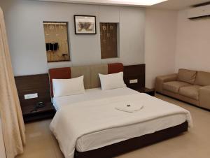 a bedroom with a large bed and a couch at hotel nova haven in Ankleshwar