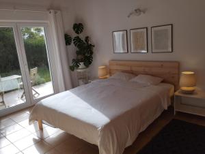 a bedroom with a white bed and a sliding glass door at Endless Summer Surf House in Aljezur