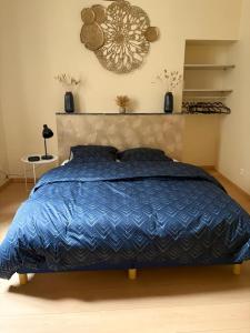 a bedroom with a bed with a blue comforter at Au Courant d'Aire! in Aire-sur-la-Lys