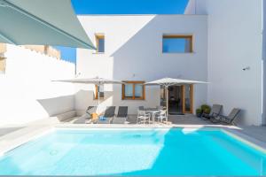 a pool with chairs and umbrellas next to a house at Nuova -Luxury Rooms & Apartment- in Olbia