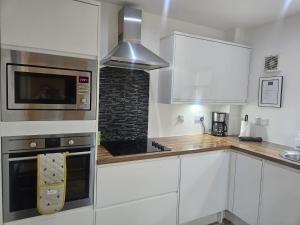 a kitchen with white cabinets and a microwave at Langley Apartment 2BR Sleeps 4 - great city centre location in Inverness