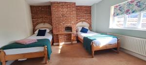 two twin beds in a room with a brick wall at Earsham Street House in Bungay