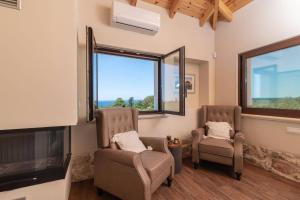 a living room with two chairs and a flat screen tv at Villa Idalia Retreat by Villa Plus in Koiliomenos