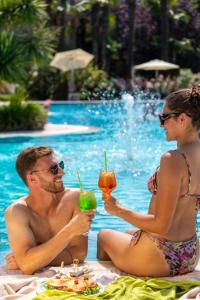 a man and woman sitting next to a pool with drinks at Astoria Resort in Riva del Garda