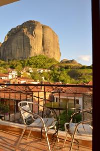 a balcony with two chairs and a table and a mountain at Guesthouse Lithos in Kalabaka