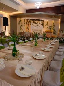 a long table with white plates and wine glasses at The Lumber Hotel and Resort in Virac +18 photos
