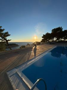 a person standing next to a swimming pool with the sunset at Magnifique T2 Athena in Bandol