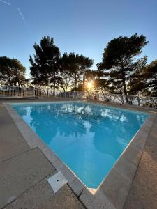a blue swimming pool with trees in the background at Magnifique T2 Athena in Bandol