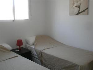 a bedroom with two beds and a red lamp on a table at Casa Lucero in Rojales