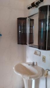 a bathroom with a white sink and a mirror at Suítes Recanto Renascer in Caraguatatuba