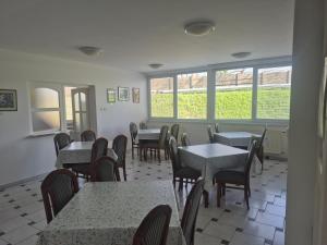 Un comedor con mesas y sillas y ventanas. en Torna Club Panzió, en Békéscsaba