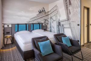 柏林吕措酒店的一间有一张大床和两把椅子的卧室