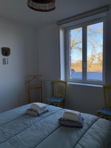 a bedroom with a bed and two chairs and a window at Maison familiale 8 pers, Le Marais des Mielles in Bréhal