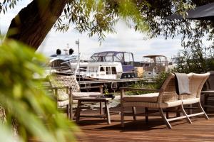 un grupo de sillas, una mesa y un barco en Precise Resort Schwielowsee - Hotel, en Werder