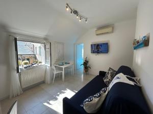 Una sala de estar con un sofá azul y una ventana. en Sogni al Sole by Holiday World, en Génova