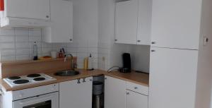 una cucina con mobili bianchi e un lavandino di Centraal appartement met tuintje, vlak bij zee a De Panne Altre 6 foto