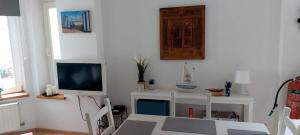 a living room with a table and a television at Centraal appartement met tuintje, vlak bij zee in De Panne