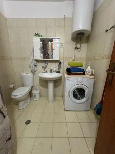 a bathroom with a toilet a sink and a washing machine at Volga Cozy Apartment in Durrës