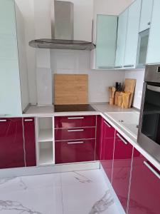 a kitchen with red cabinets and white counters at Apartman SIX in Brela +9 photos