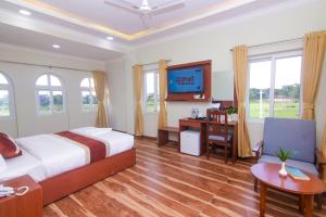 una camera da letto con un letto, una scrivania e una TV di Hotel Yatra Sauraha Pvt Ltd a Jhawāni