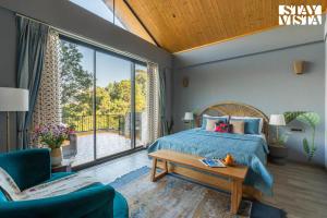 卡绍利StayVista at Thelma Cottage with BBQ & Bonfire的一间卧室，里面有一张床和一扇大窗户。