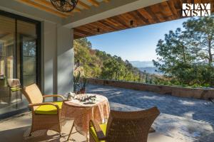 卡绍利StayVista at Thelma Cottage with BBQ & Bonfire的露台上的一张桌子和几把椅子，可以欣赏美景