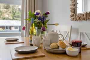 Una mesa con platos de comida y un jarrón de flores. en The Snug - Brixham, en Brixham