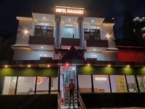 RudraprayāgHotel Mahadev的一名妇女晚上站在酒店大堂前