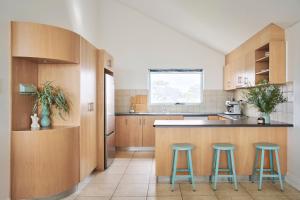 a kitchen with wooden cabinets and two blue stools at Waves for Daze in Middleton