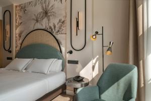 a bedroom with a bed and a green chair at Vincci Maritimo in Barcelona