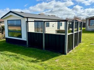 a small house with a wooden fence in a yard at Chalet direct aan Waddenzee in Westerland +12 photos