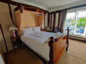 a bedroom with a bed with a wooden frame and a window at The Crown Hotel in Framlingham +2 photos