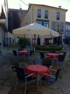 a table and chairs with an umbrella in a courtyard at Hotel Pinzon in Baiona