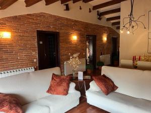 a living room with two white couches and a brick wall at Les Golfes de Can Mascarbo, mimar-te en un confortable espai in Sant Hilari Sacalm