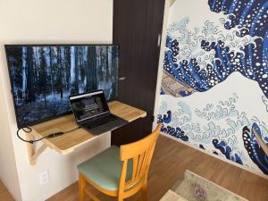 a room with a desk with a laptop on a wall at Share House Kofu - Digital check-in only in Kofu