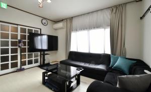 a living room with a black couch and a tv at Share House Kofu - Digital check-in only in Kofu