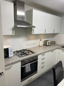 a kitchen with white cabinets and a stove top oven at Two bedroom apartment set in communal gardens in Verwood