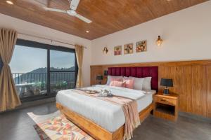 une chambre avec un grand lit et une grande fenêtre dans l'établissement Alaya Stays Evara - 2 BHK Hilltop Hideaway With Balcony, Fireplace & Scenic Views, à Mussoorie